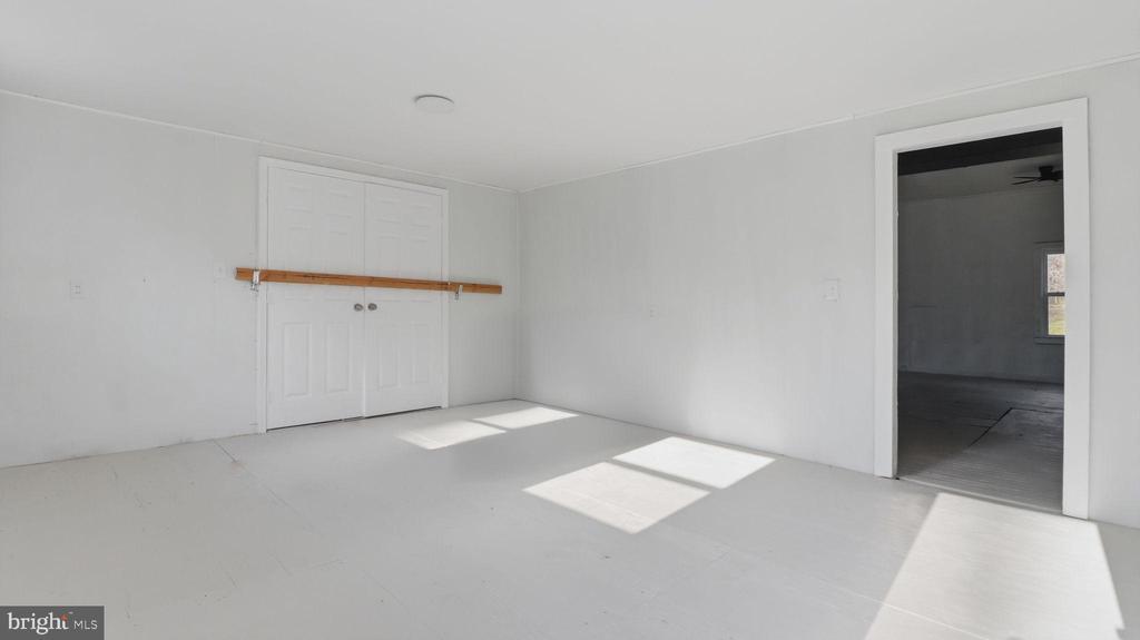 Empty room with white walls, double closet doors, and sunlight across the floor.