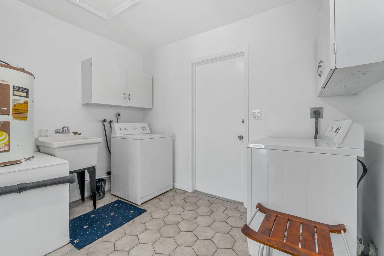 Laundry room with a washer and dryer, utility sink, and hexagonal tile floor.