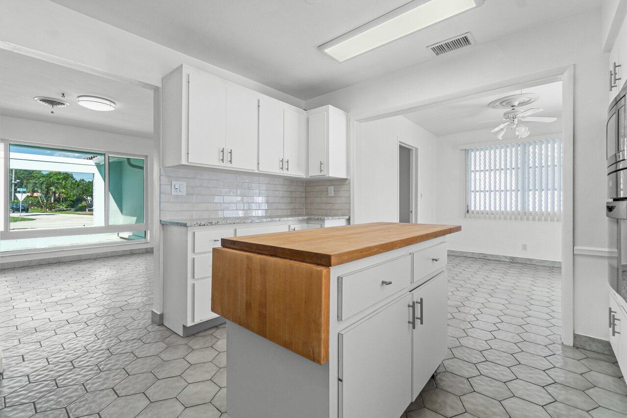 Vacant kitchen with white cabinets, a large wood-topped island, and geometric tile floors.