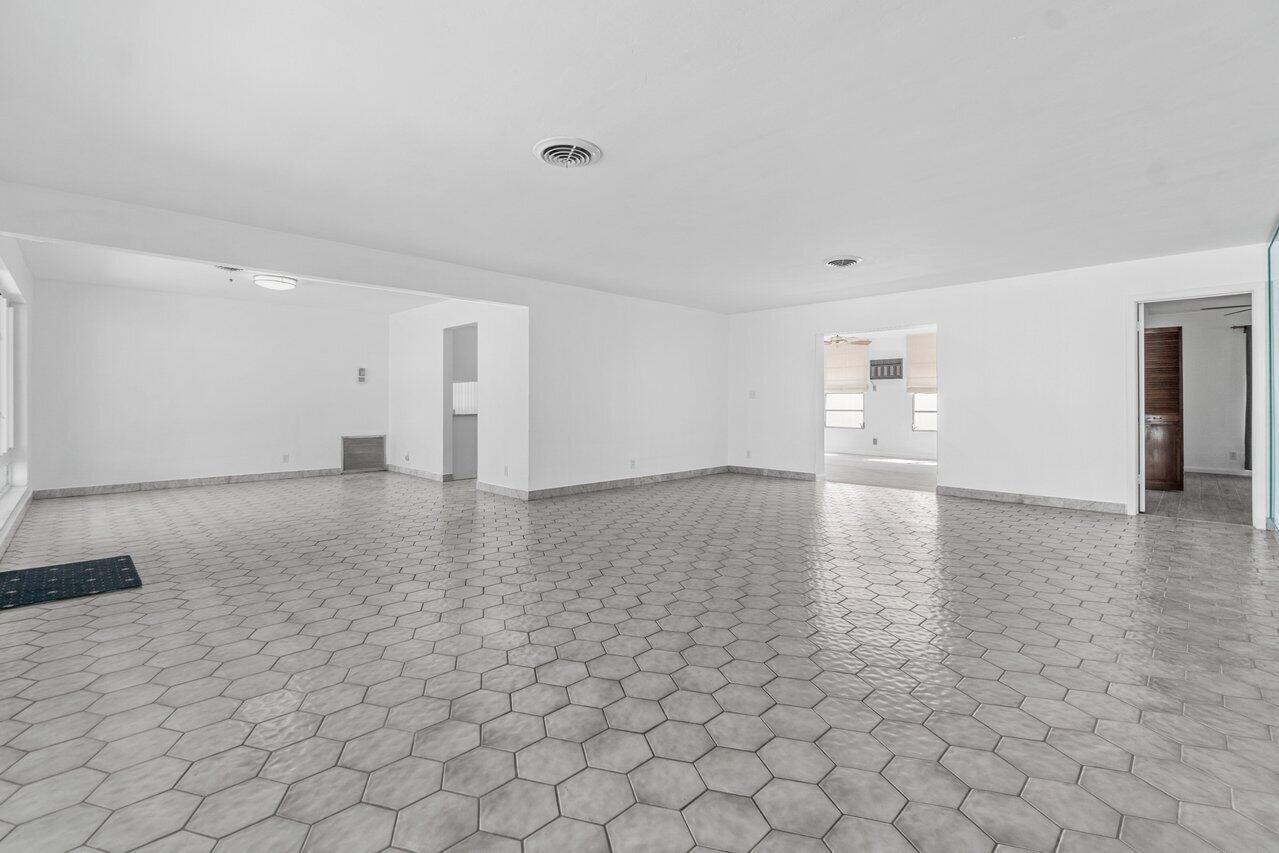 Empty room with gray hexagonal tile flooring and openings to adjoining rooms.