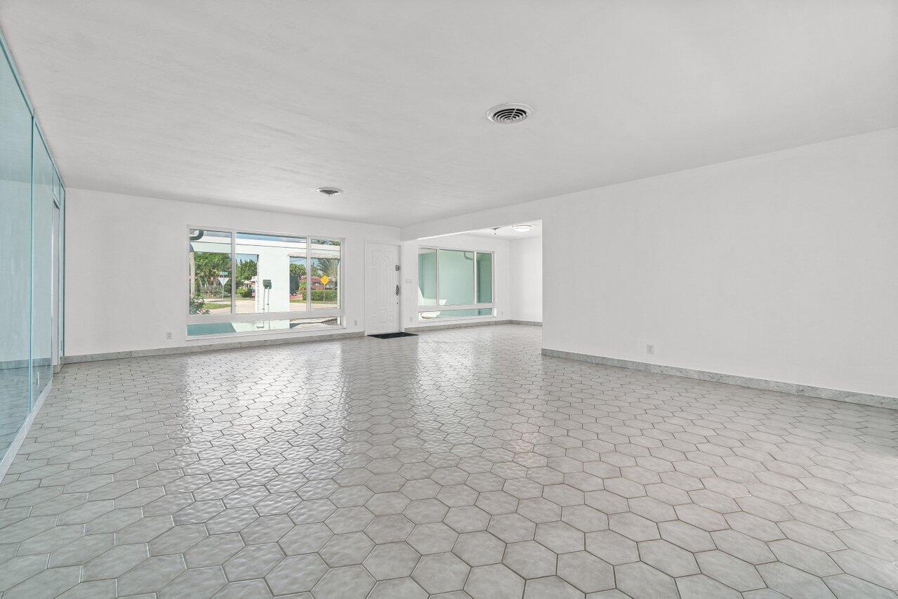 Vacant interior with large windows and gray hexagonal tile flooring.
