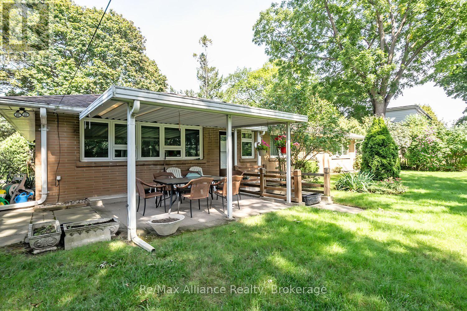 Brick house with a covered patio and outdoor dining set opening onto a leafy lawn.
