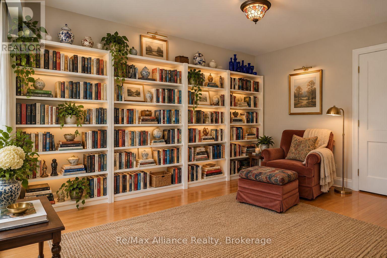 Furnished library with book-lined white shelves and a rust-colored armchair and ottoman.