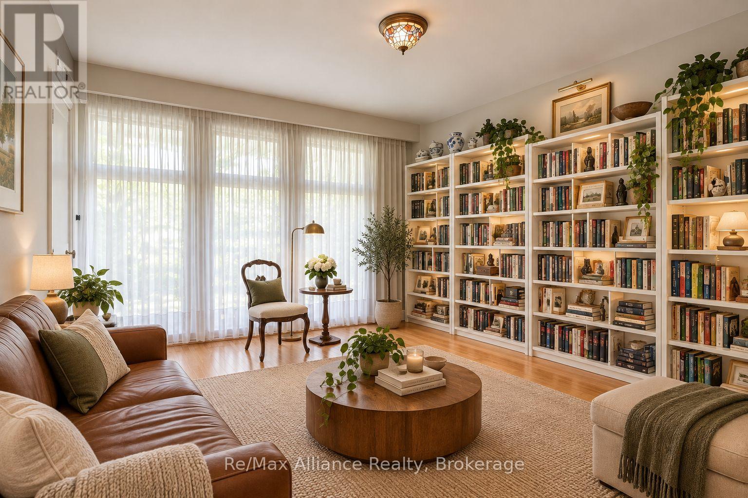 Living room with floor-to-ceiling bookcases, broad curtained windows, and a leather sofa.
