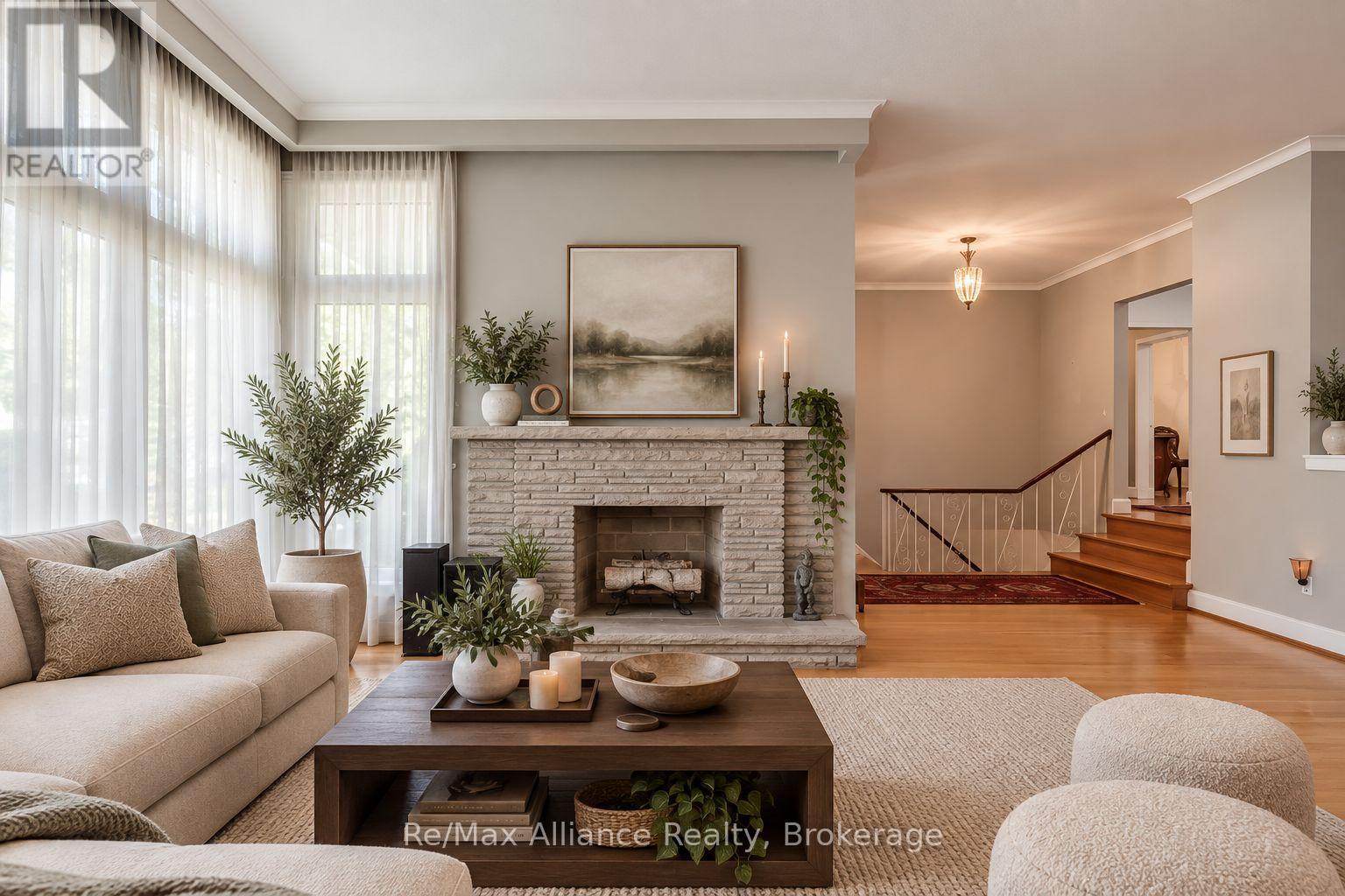 Living room with a pale stone fireplace, tall curtained windows, and a cream sectional sofa.