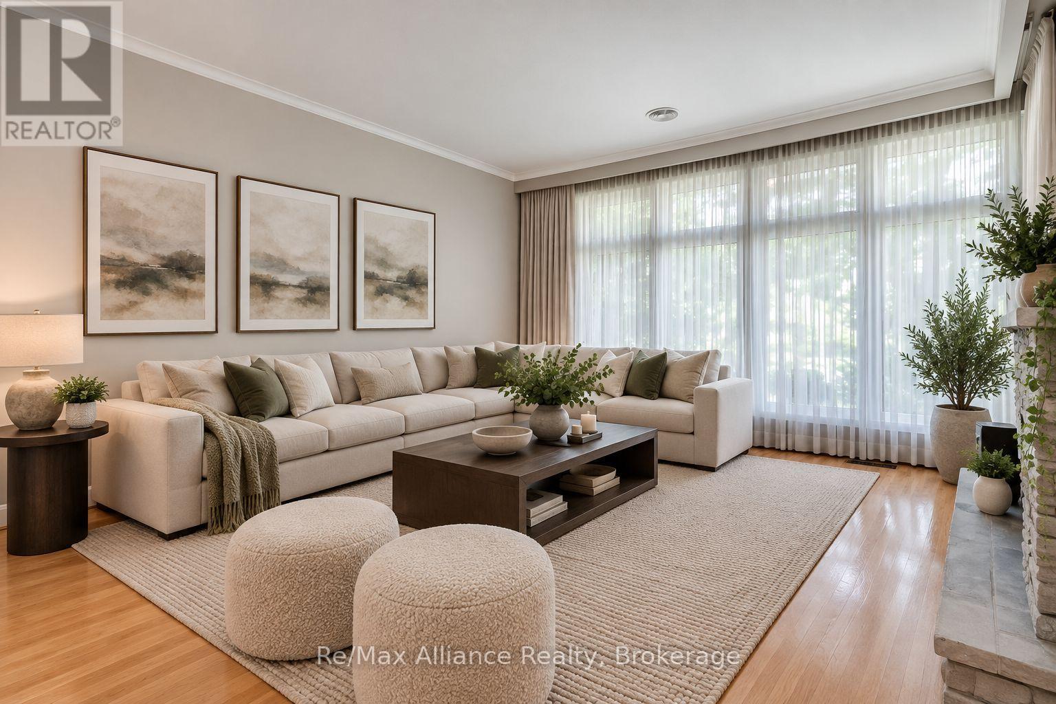 Living room with a cream sectional, three abstract artworks, and tall windows with sheer curtains.