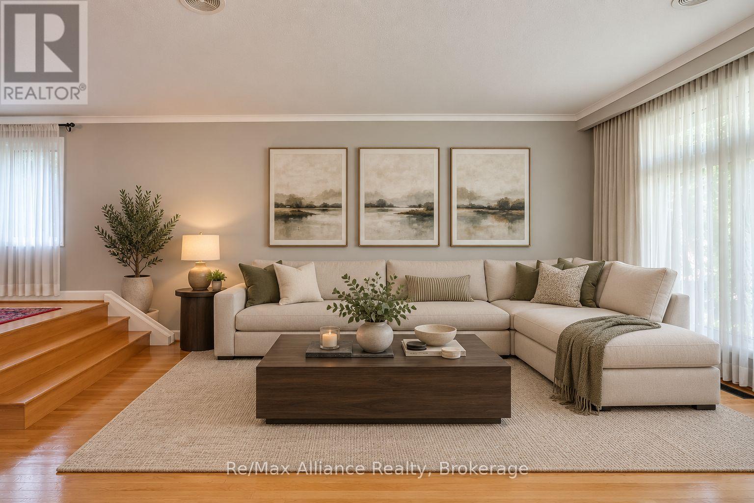 Living room with a cream sectional, three landscape prints, and hardwood stairs.