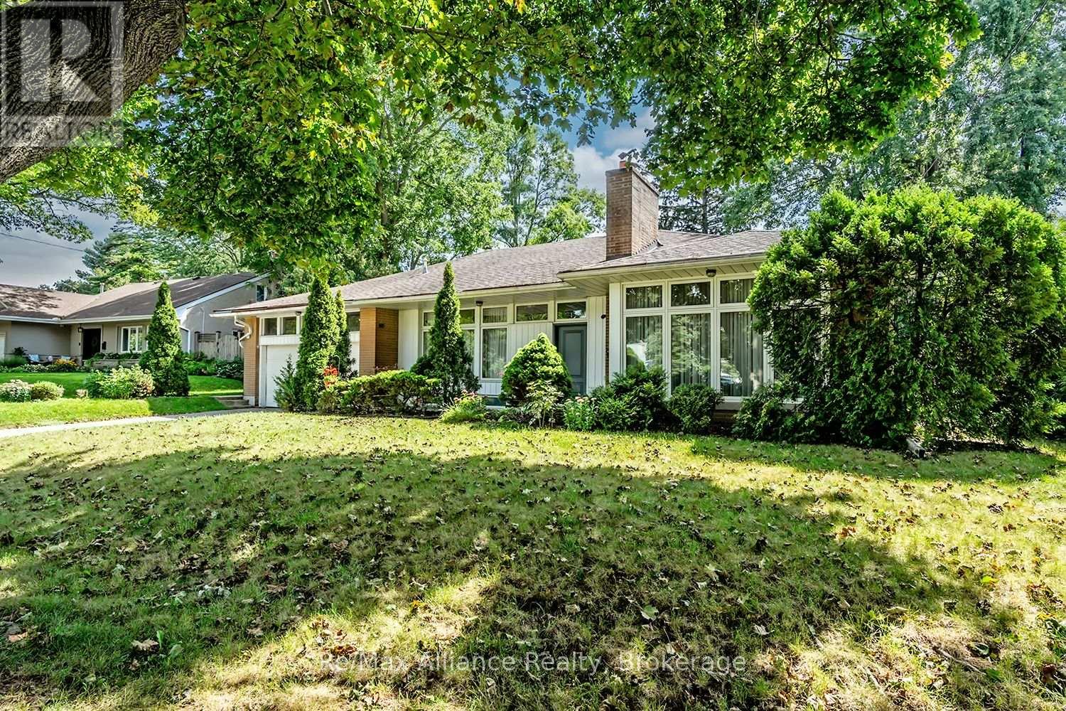 Single-story house with an attached garage, landscaped front yard, and mature trees.