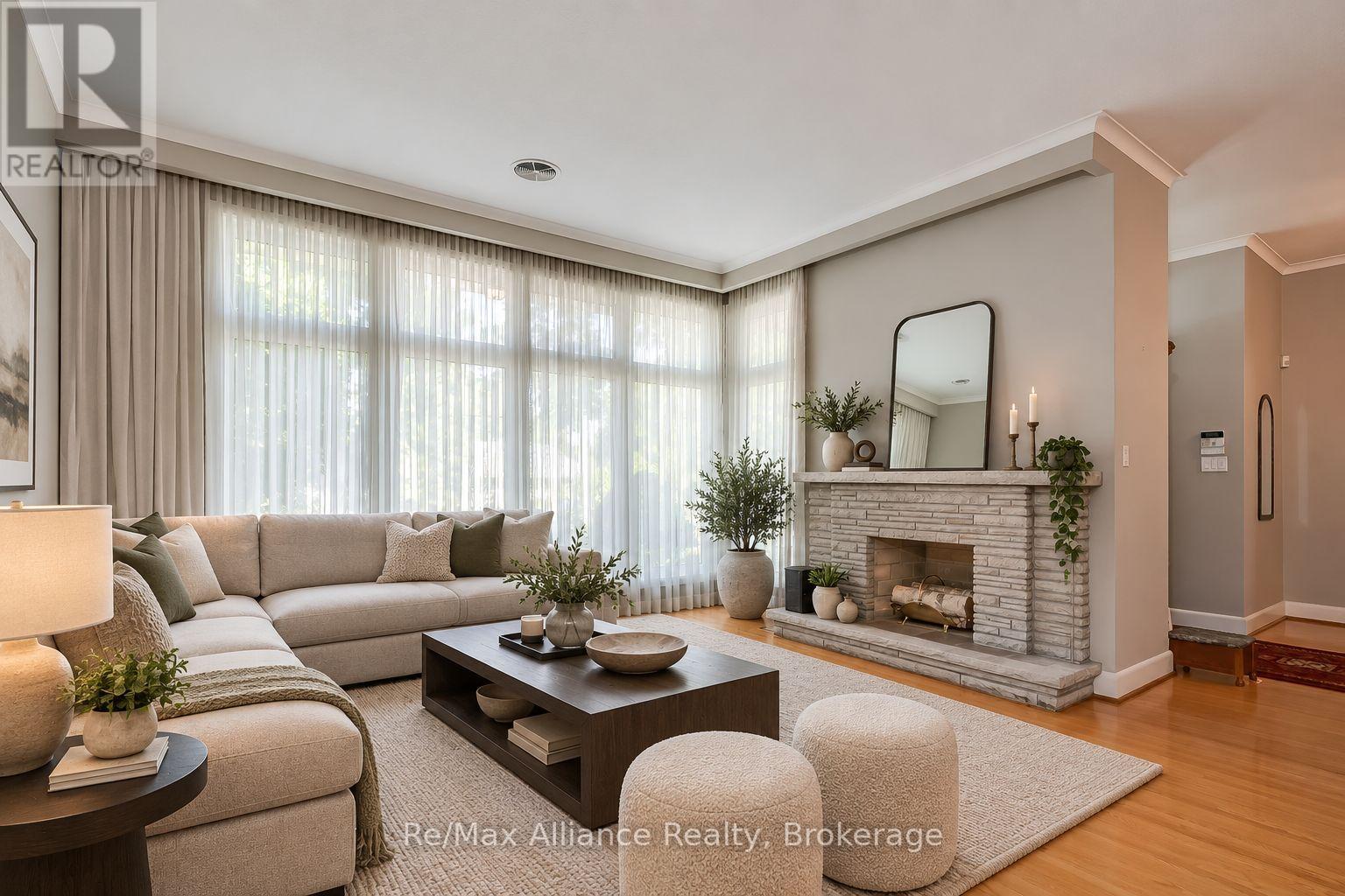 Staged living room with a cream sectional, tall curtained windows, and a stone fireplace.