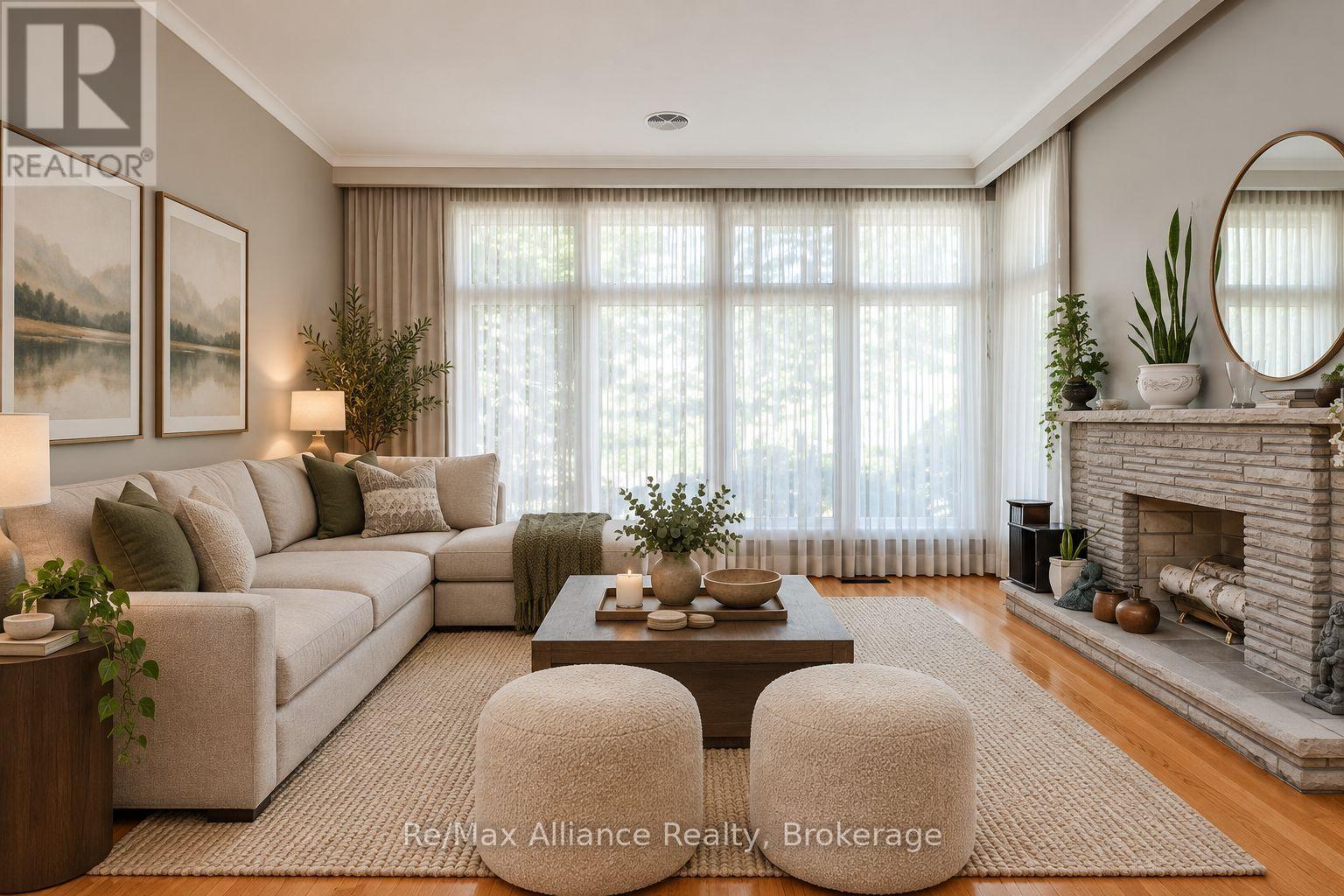 Living room with a cream sectional, round ottomans, broad curtained windows, and a stone fireplace.