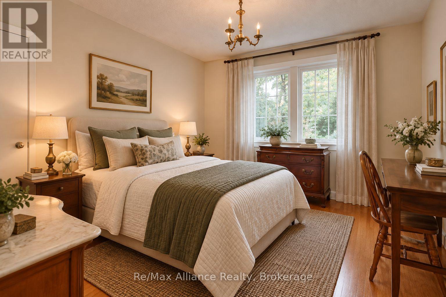 Furnished bedroom with a white quilted bed, olive accents, dark wood furniture, and a large curtained window.