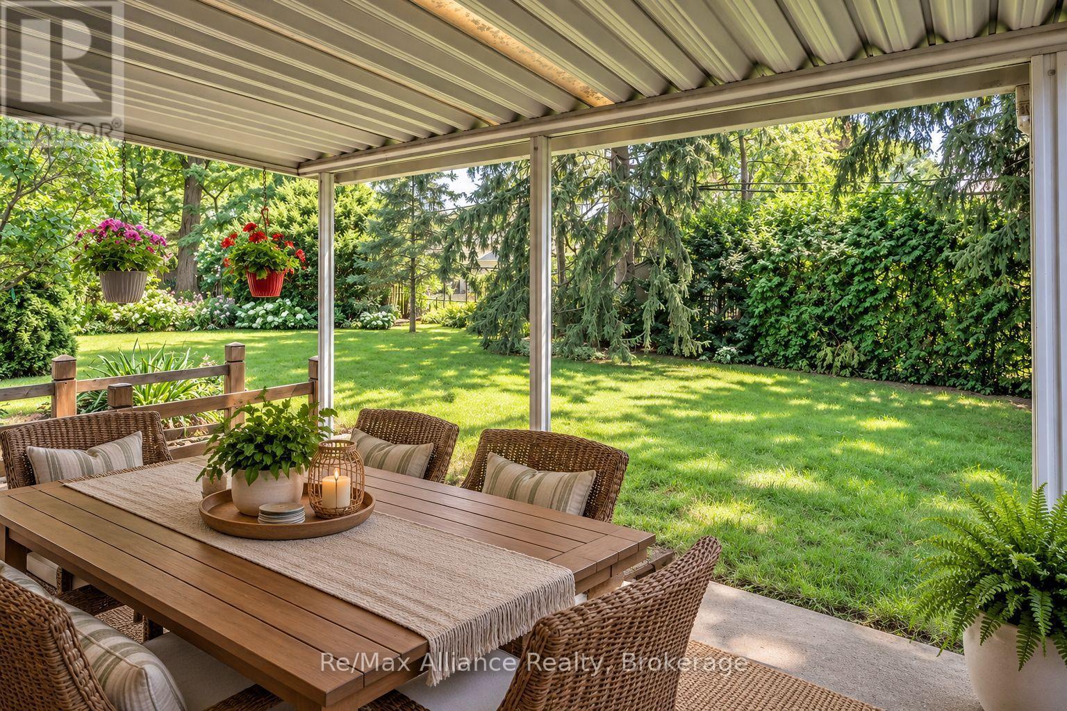 Covered patio with a wooden dining table and woven chairs overlooking a lush garden.
