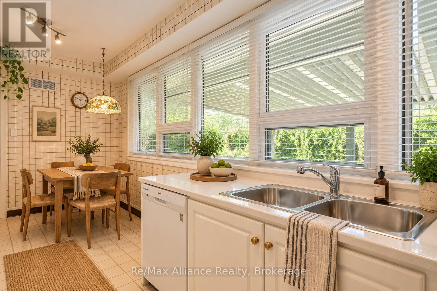 Bright tiled kitchen with a double sink, wide windows, and a wooden dining nook.