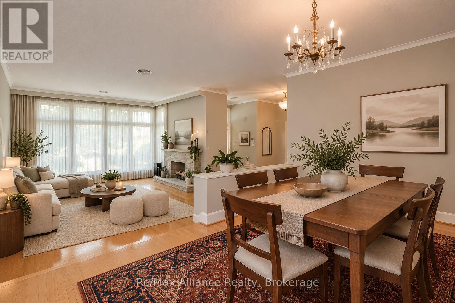 Open-plan living and dining room with a stone fireplace, chandelier, and large curtained windows.