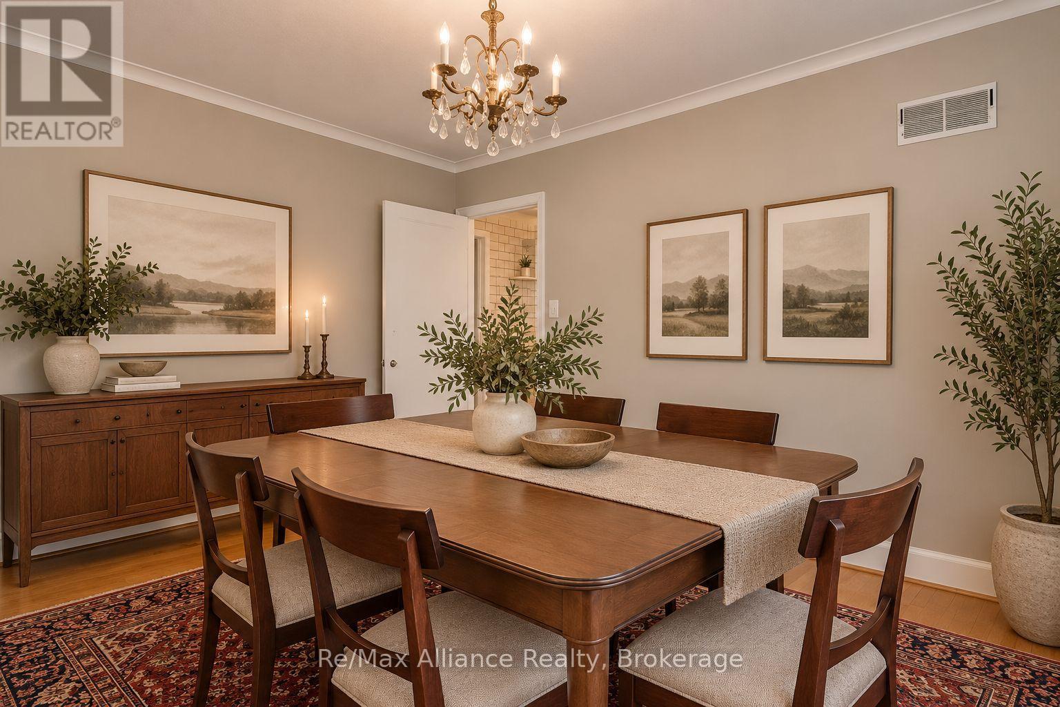 Dining room with a dark wood table, chandelier, framed landscape prints, and patterned rug.