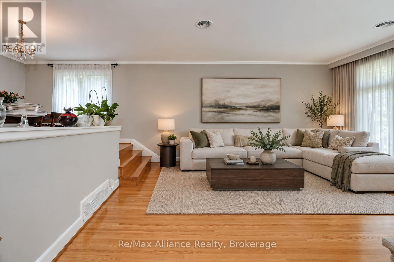 Furnished living room with a cream sectional, hardwood floors, and large abstract landscape artwork.