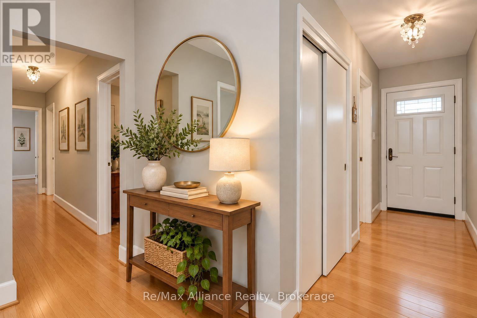 Entry hall with hardwood floors, a round mirror, and a console table with plants and a lamp.