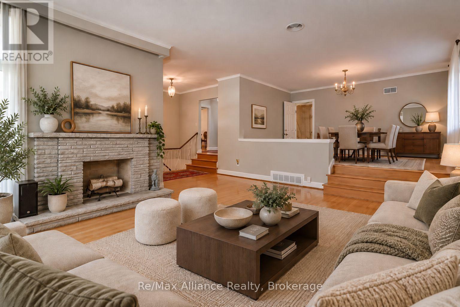 Living room with a stone fireplace opening to a raised dining area.