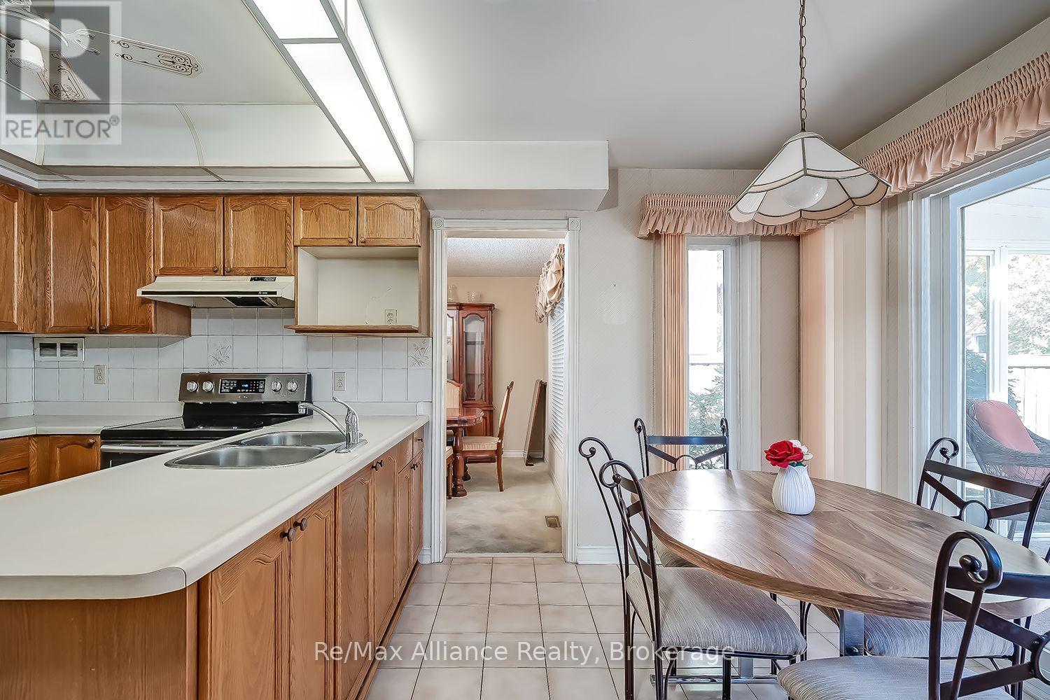 Kitchen with warm wood cabinetry and a peninsula opening to a dining area beside patio doors.