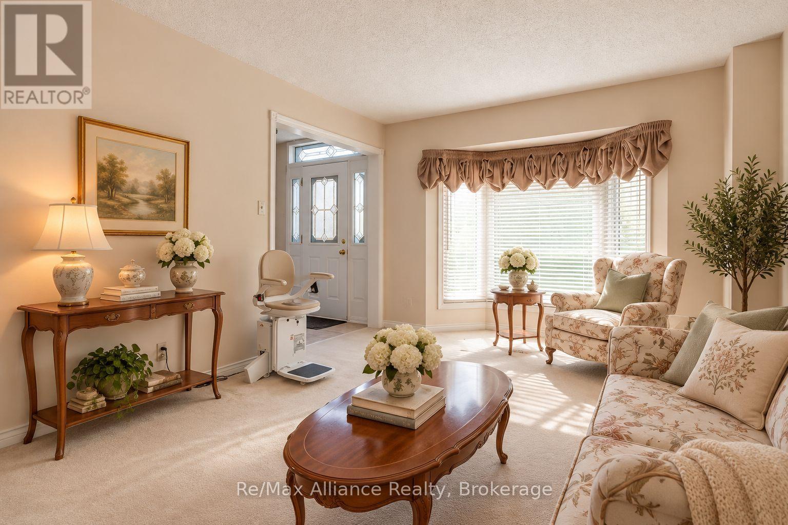Living room with floral seating, an oval wooden coffee table, and a stair lift beside the entry.
