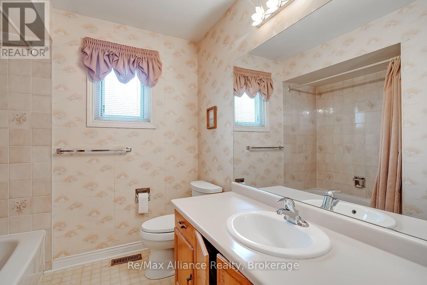 Bathroom with a double-sink vanity, wood cabinetry, and a tiled shower enclosure.
