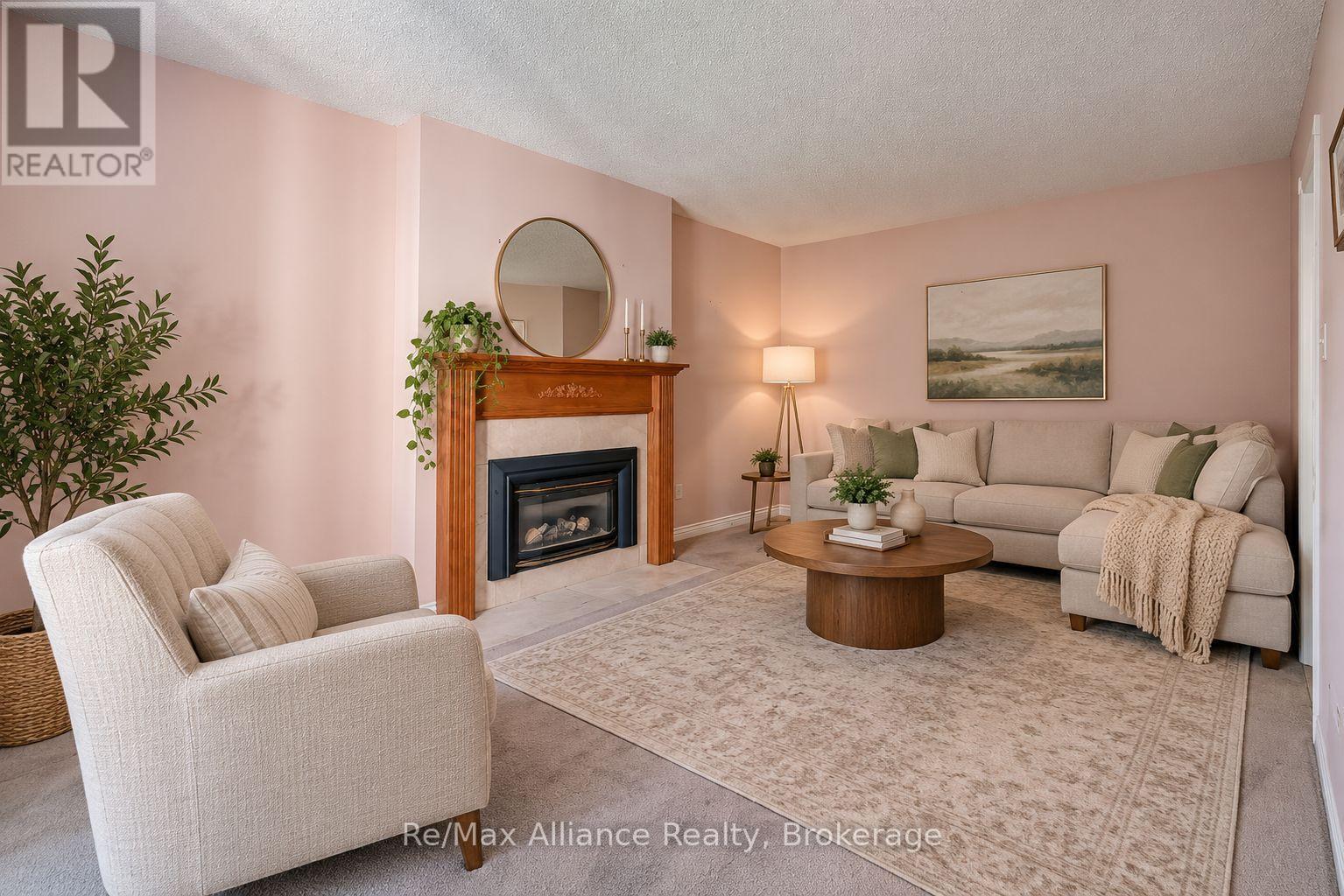 Staged living room with a wood-trimmed fireplace, beige sectional, and round coffee table.