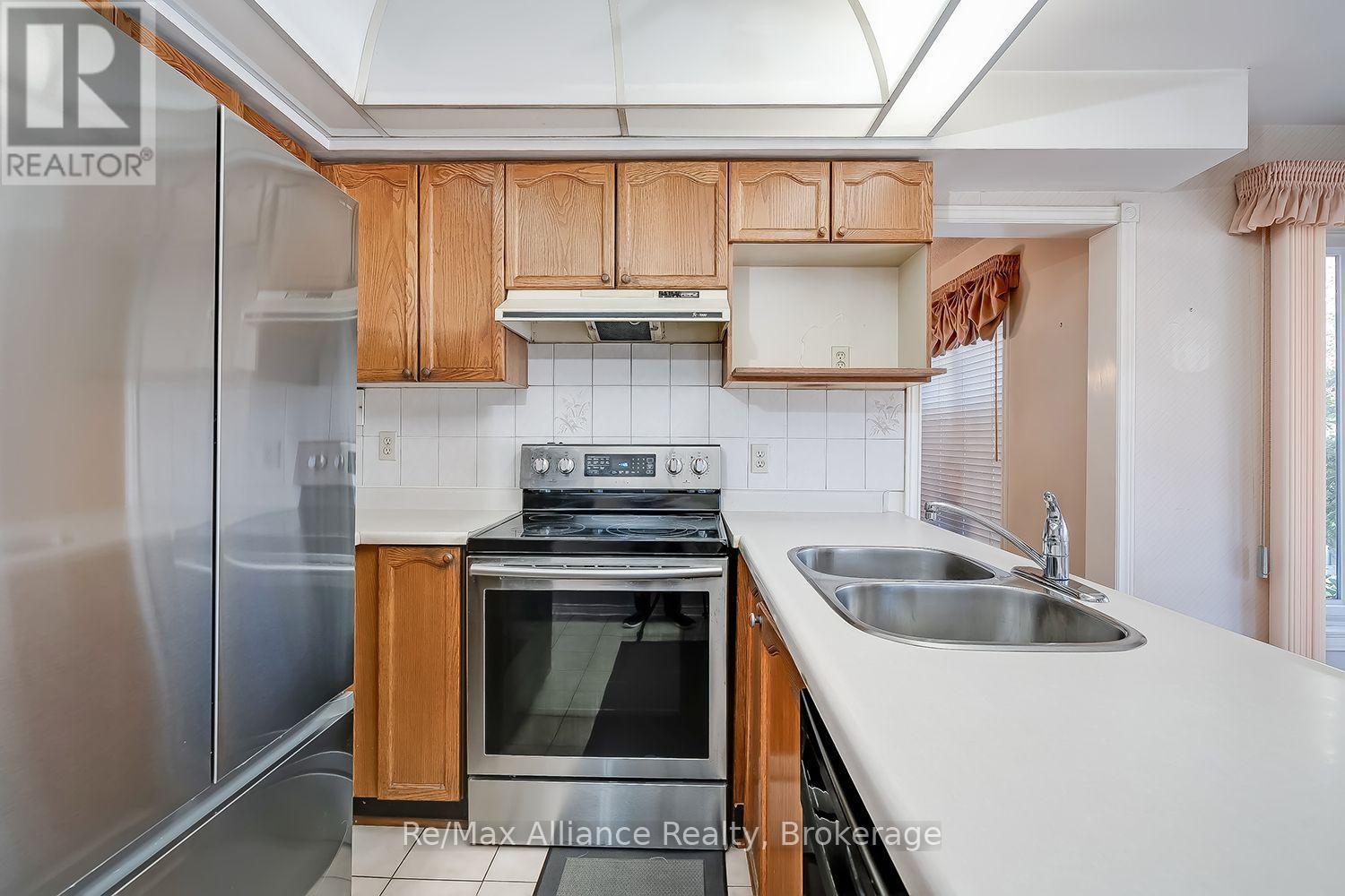 Kitchen with wood cabinetry, stainless-steel appliances, skylight, and double-basin sink.
