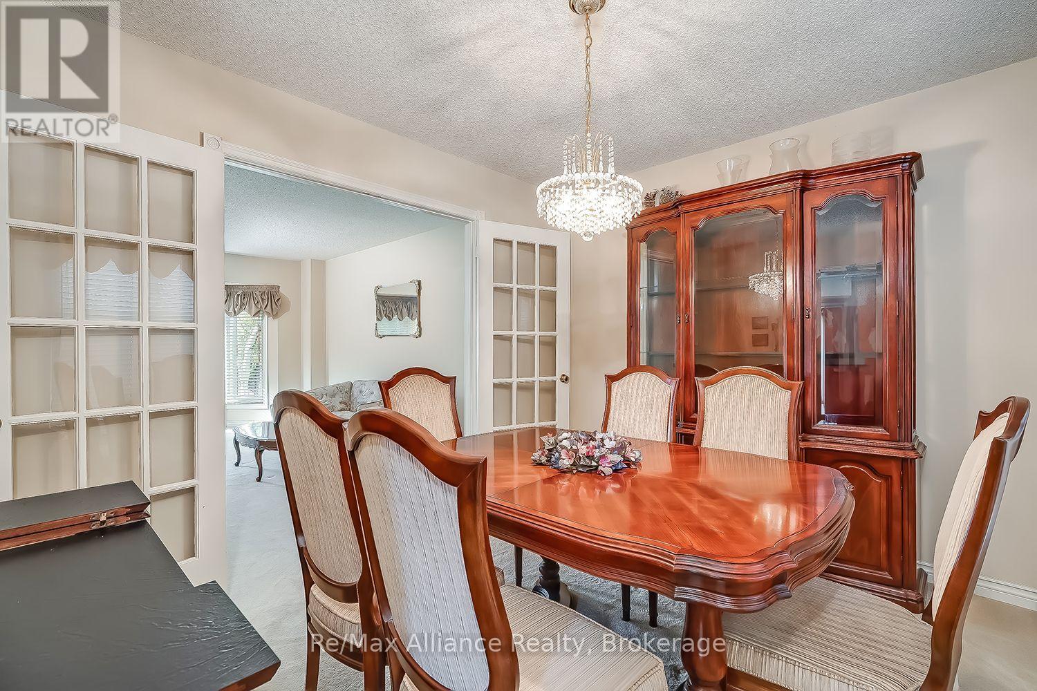 Dining room with a polished wood table, glass-front china cabinet, and chandelier.