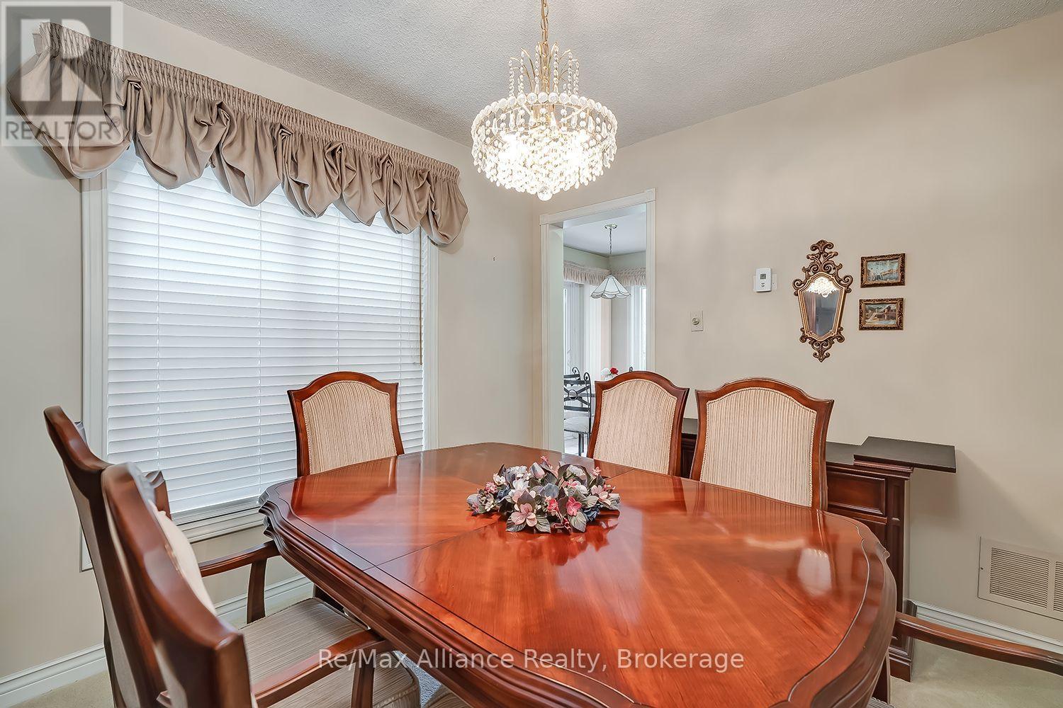 Dining room with a polished wooden table, upholstered chairs, and a crystal chandelier.
