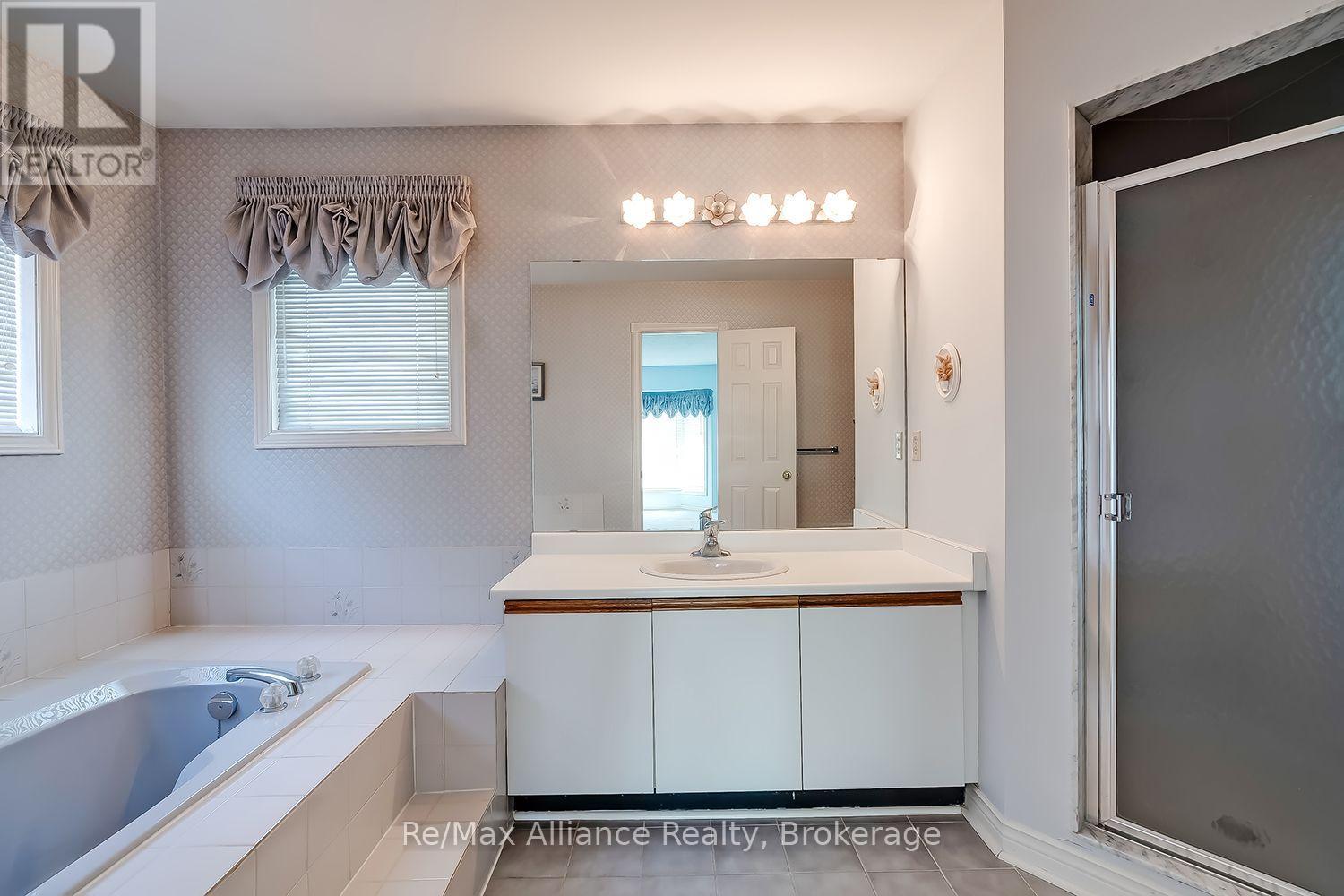 Bathroom with a corner bathtub, wide vanity, large mirror, and glass shower enclosure.