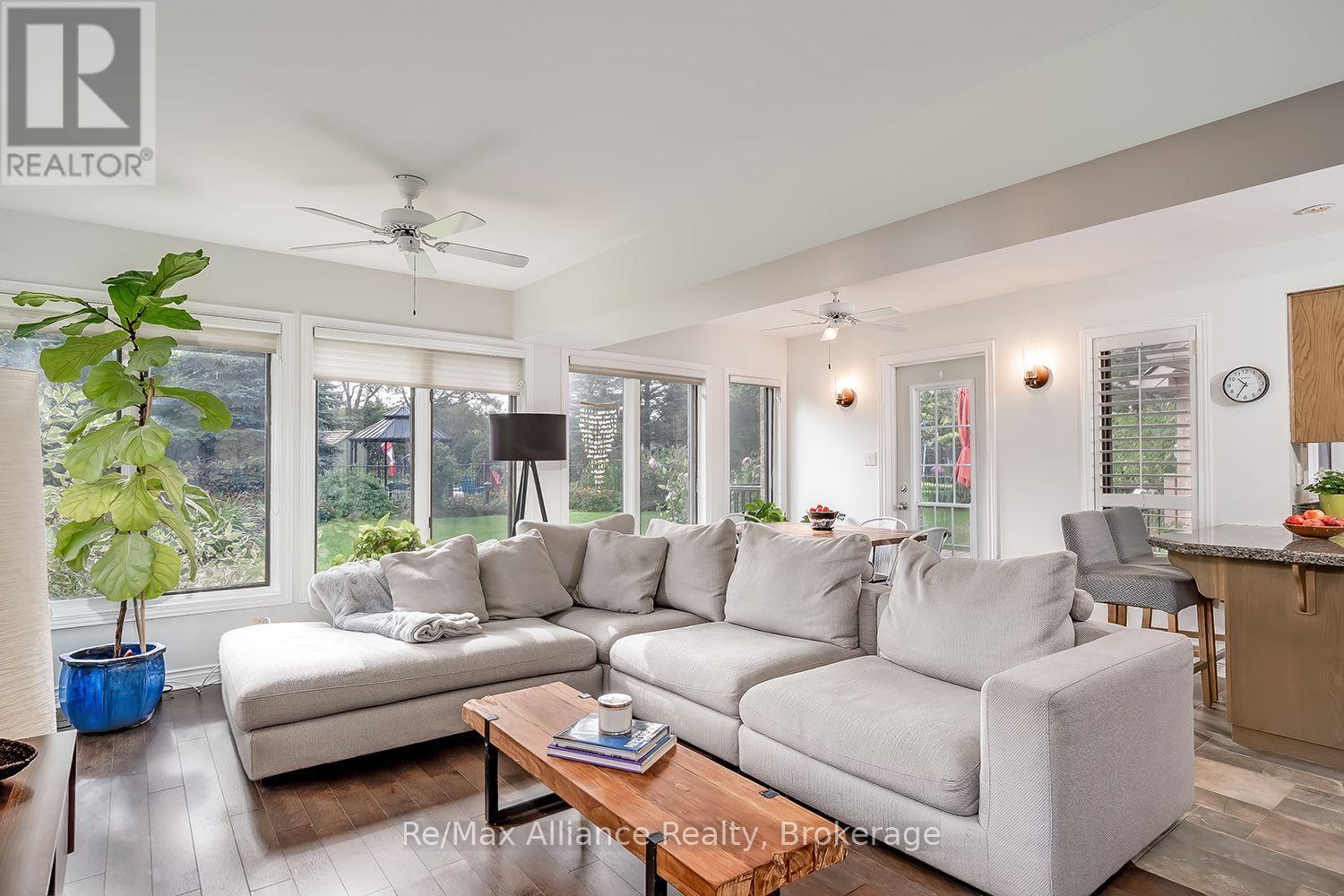 Bright living room with a large sectional, wood coffee table, and garden-facing windows.