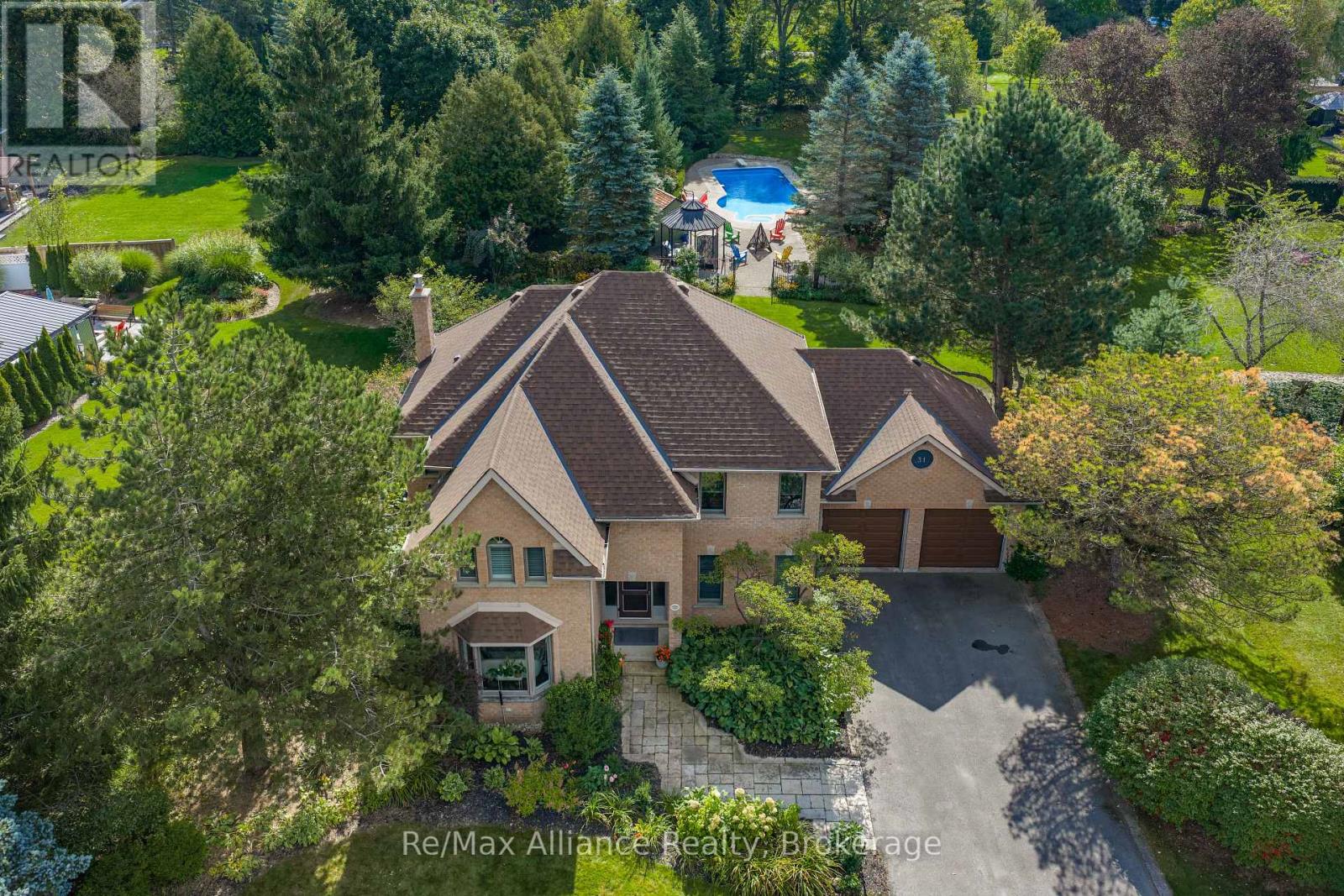 Aerial view of a brick house with a landscaped yard and backyard swimming pool.
