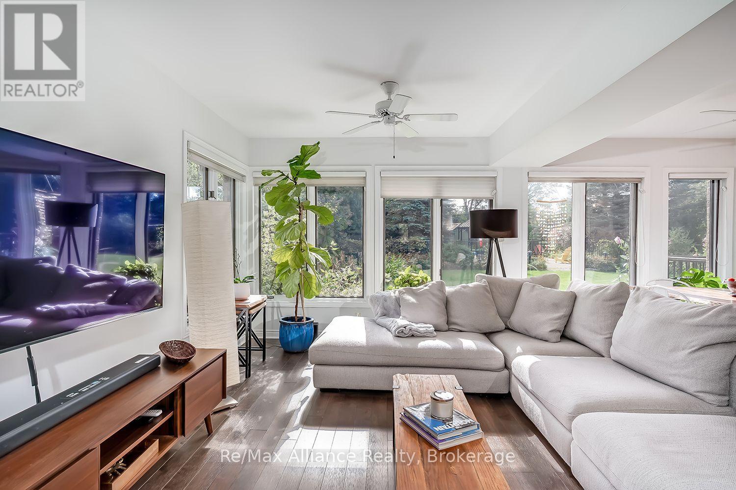 Living room with a gray sectional, wall-mounted television, and broad windows overlooking the backyard.