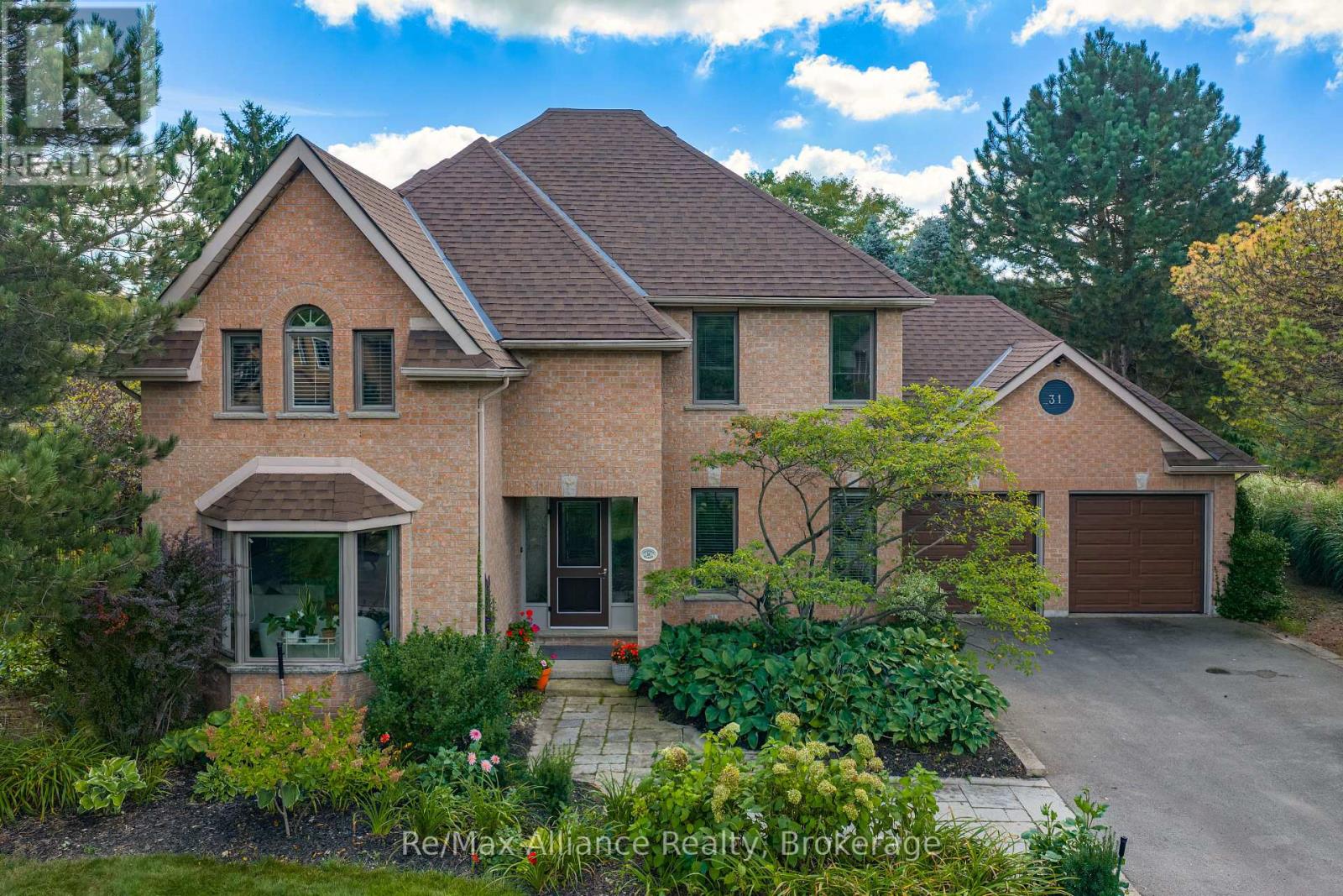 Two-storey brick house with multiple gables, landscaped gardens, and an attached double garage.