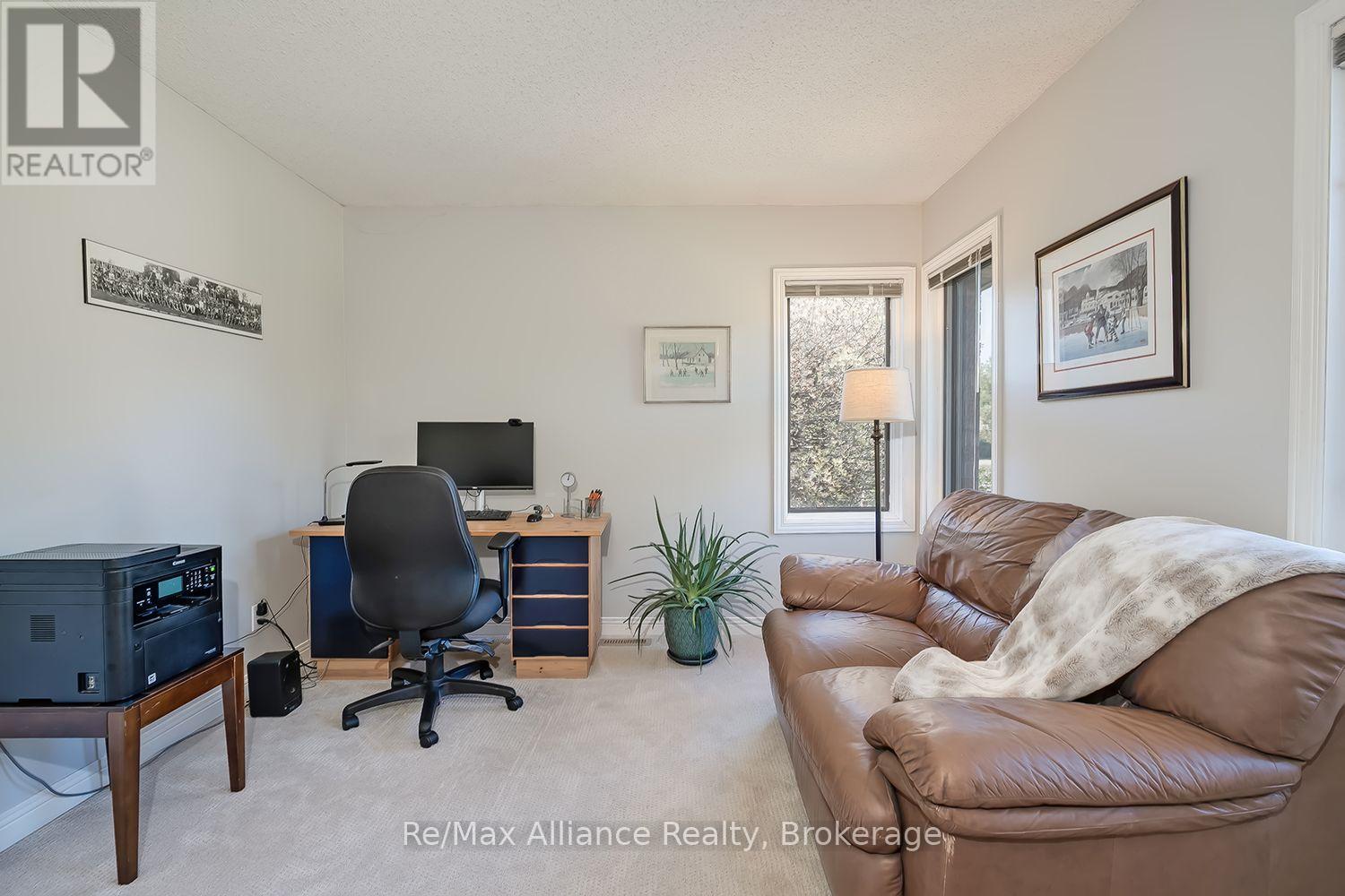 Furnished home office with a desk and printer beside a brown leather sofa.