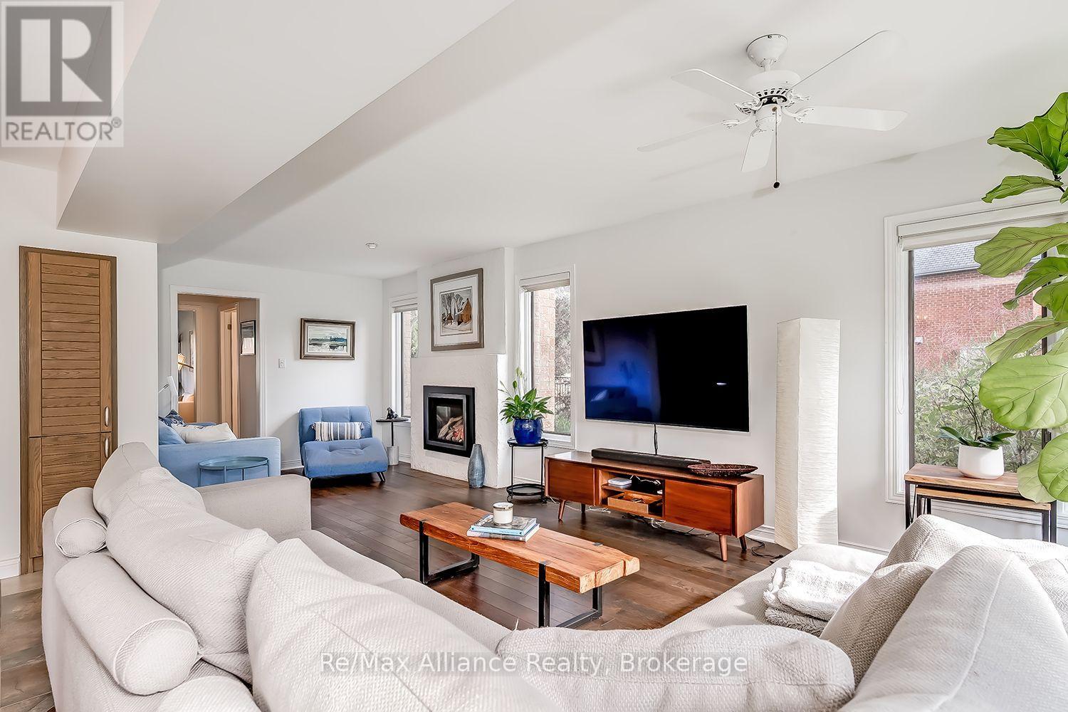 Living room with white sofas, blue chairs, a gas fireplace, and large windows.