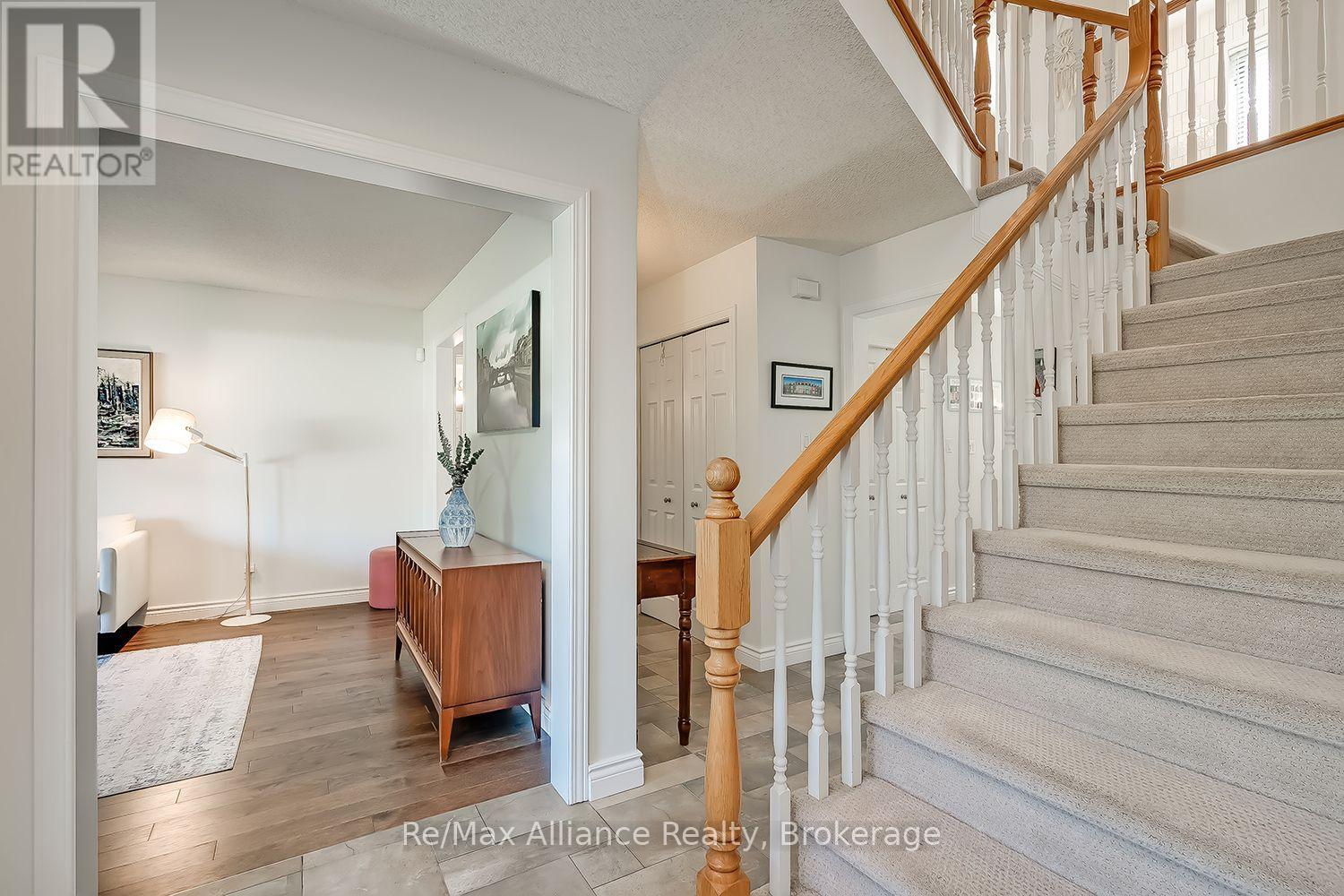 Foyer with a carpeted staircase, white balusters, wood handrail and an adjoining sitting area.