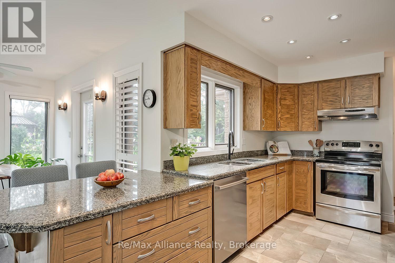 Kitchen with oak cabinetry, granite counters, stainless steel appliances, and a large peninsula.