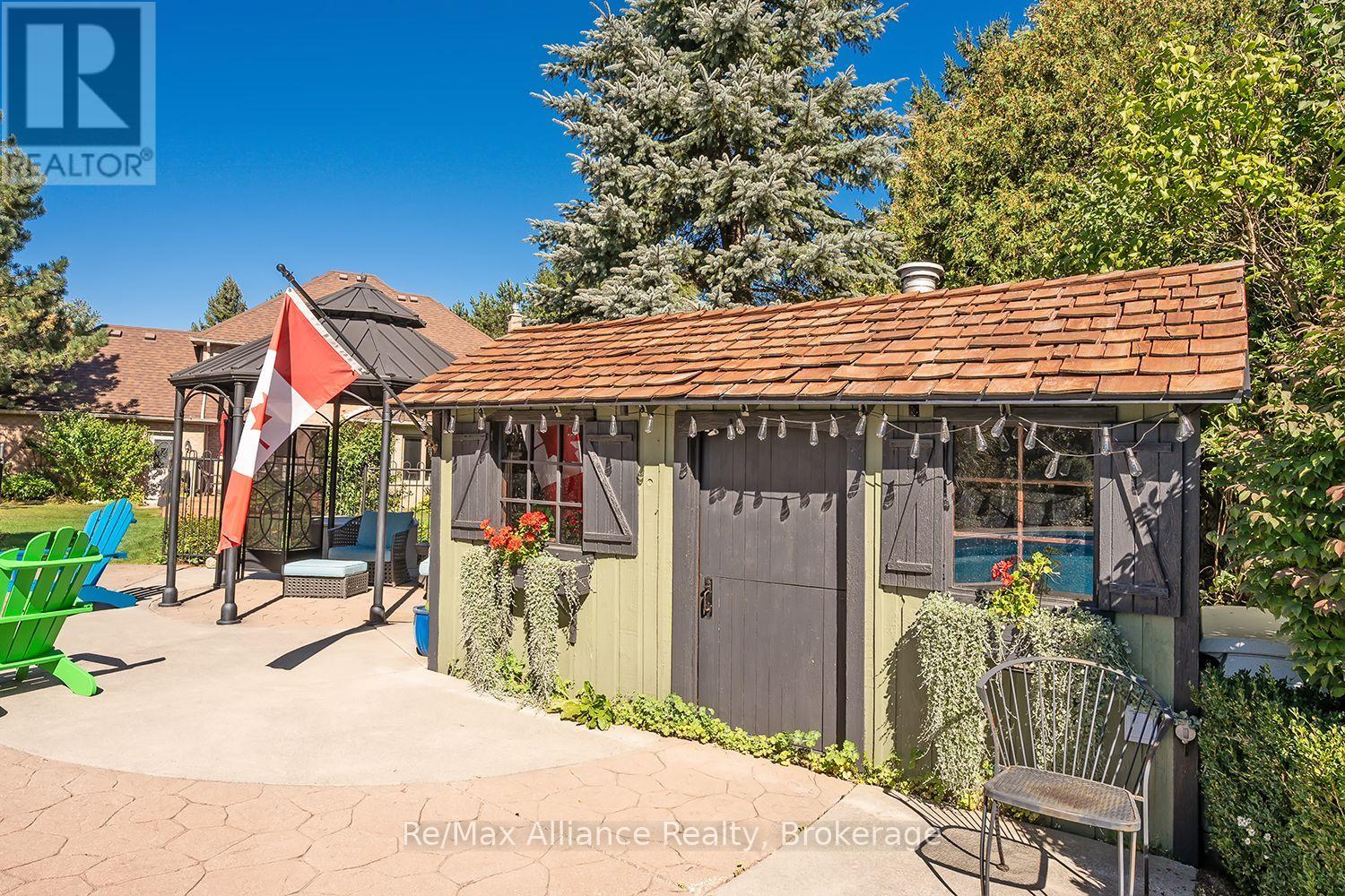 Backyard pool cabana beside a paved patio, with outdoor chairs and a Canadian flag.