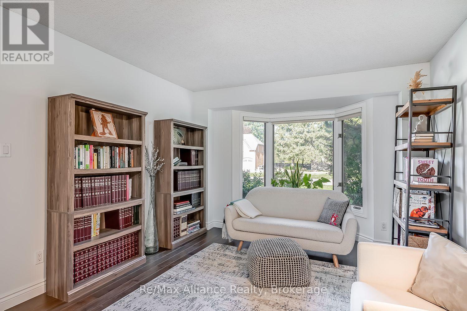 Living room reading area with bookcases, cream seating, and a large bay window.