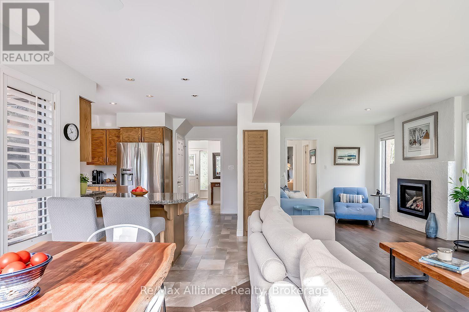 Open-plan kitchen and living room with warm wood cabinets, granite island, white sofa, and fireplace.