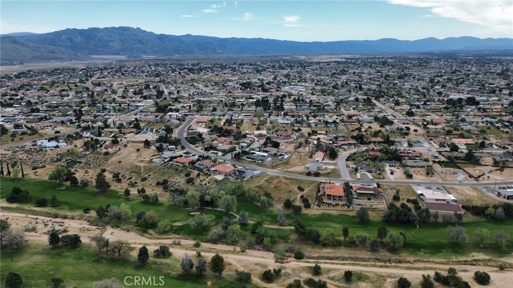 Aerial view of a residential area with green open space and mountains in the distance.