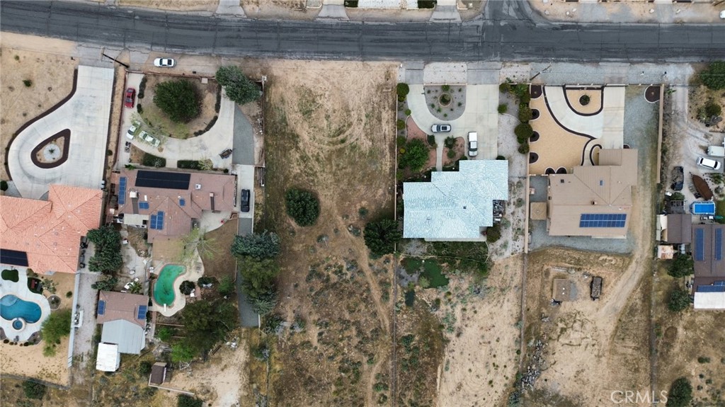 Aerial view of a vacant parcel between homes, with dry ground and street frontage.