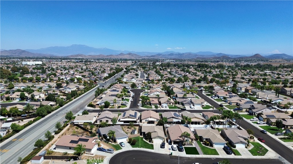 Aerial view of suburban homes with streets and distant mountains.
