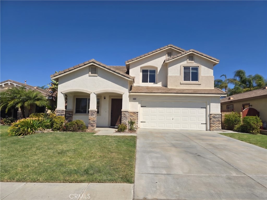 Two-story stucco home with a tiled roof, two-car garage, wide driveway, and front lawn.
