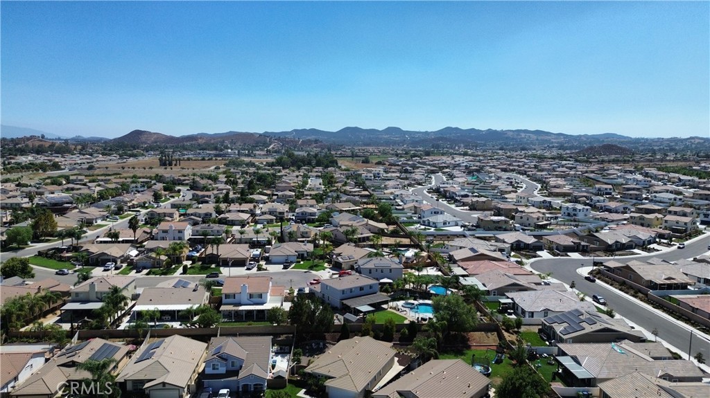 Aerial view of homes and curving streets, with backyard pools and hills in the distance.