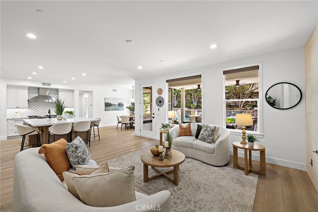 Open-plan living room and kitchen with a large island and windows overlooking a landscaped yard.