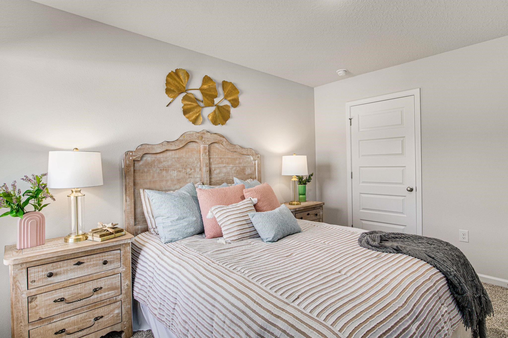 Bedroom with striped bedding, pastel pillows, and a rustic wood headboard.