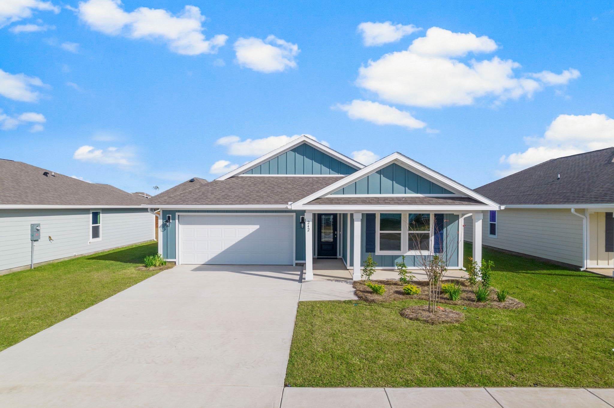 Blue-gray single-story home with a two-car garage, covered porch, and landscaped front lawn.
