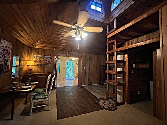 Rustic wood-paneled dining room with a vaulted ceiling, dining table, and built-in loft shelving.